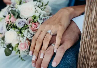 Mains avec alliances et bouquet de mariage